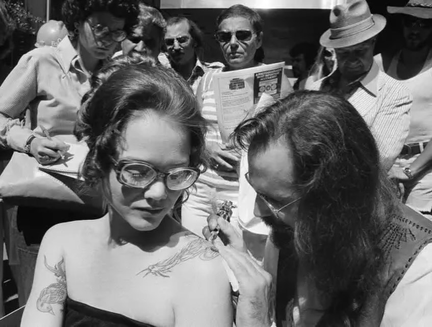 Spider Webb tattooing a bird on a woman’s shoulder outside of the Museum of Modern Art in 1976 vintage tattoo historical archive photograph