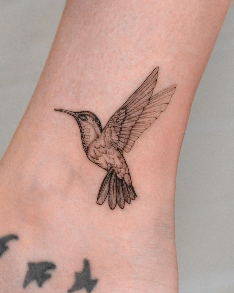 Delicate Black and Grey Hummingbird Ankle Tattoo by Vanya