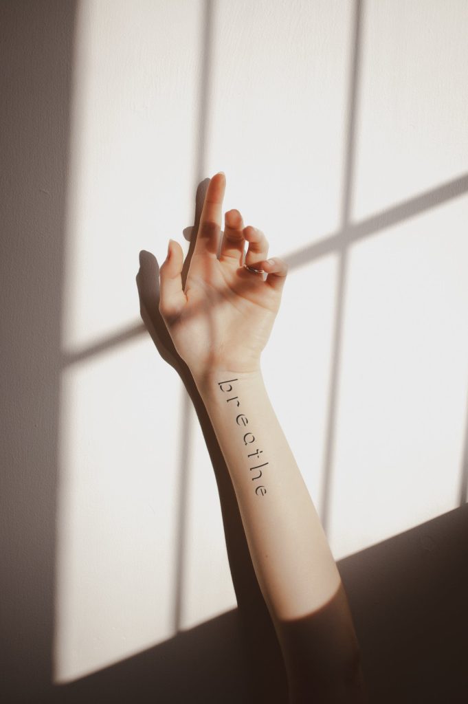 girl arm displaying breathe lettering tattoo mockup