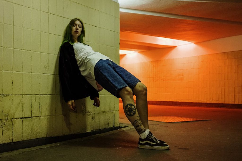 tattooed teenager leaning on subway wall