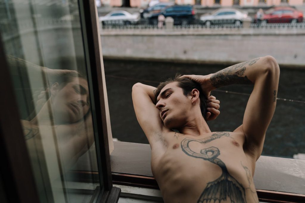 tattooed man leaning on window