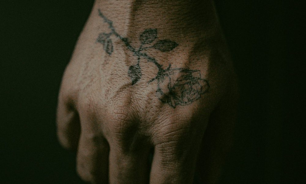 Floral tattoo with red and black ink on hand