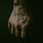 Floral tattoo with red and black ink on hand